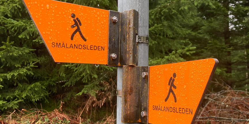 Två skyltar med vandrarsymboler sitter på en stolpe